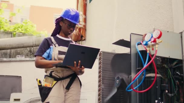 Certified technician working on outdoor hvac system, holding laptop. Competent mechanic optimizing external air conditioner performance, ensuring it operates at maximum capacity - Séquence, vidéo