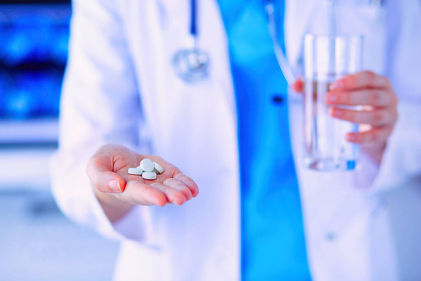 Close-up shot of doctors hands holding pills and glass of water - 写真・画像