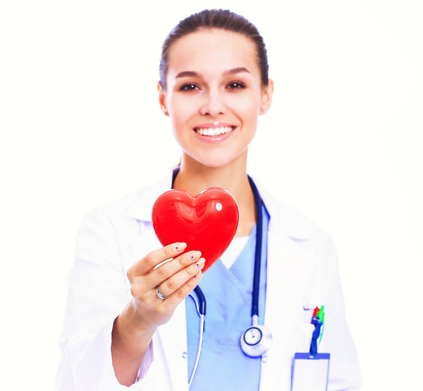 Positive female doctor standing with stethoscope and red heart symbol. - 写真・画像