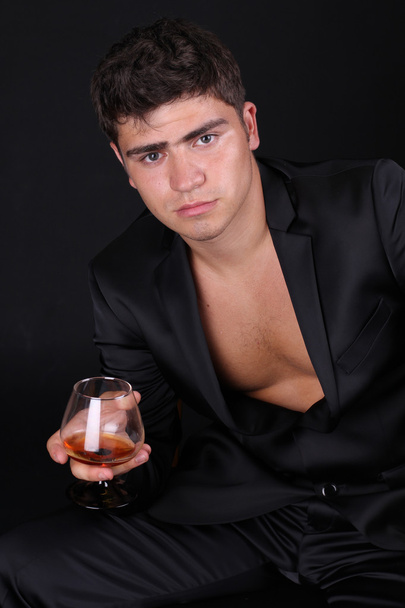 Man with glass of cognac on dark background - Valokuva, kuva