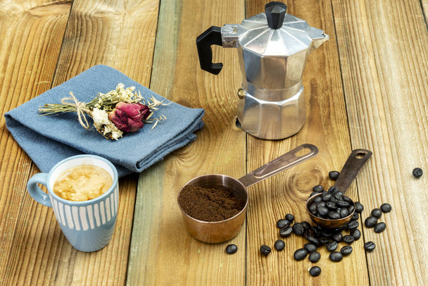 Un bodegón con café tostado, café molido en una cacerola de cobre, un expreso en una taza azul y una pequeña cafetera - Foto, imagen