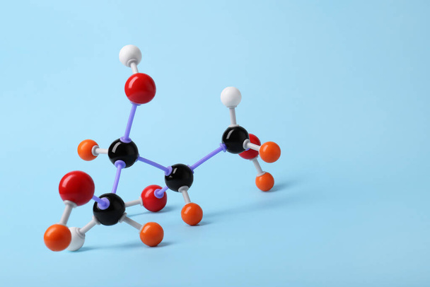 Molecule of sugar on light blue background, space for text. Chemical model - Фото, зображення