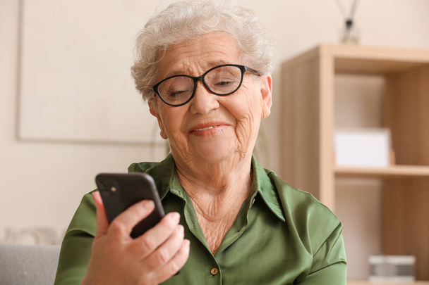 Idős nő használja a mobiltelefon otthon, közelkép - Fotó, kép