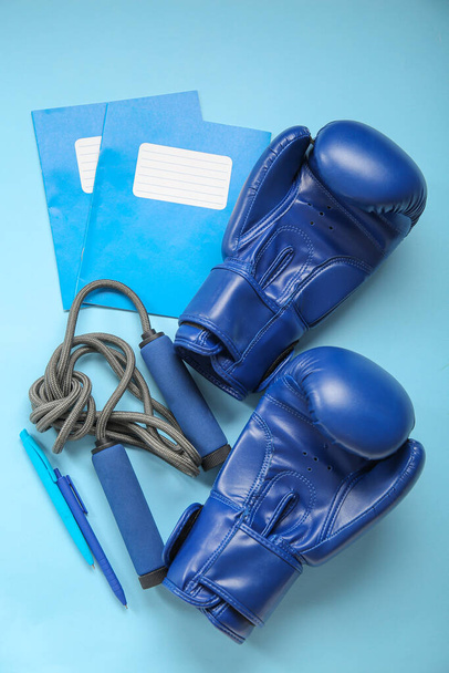 Boxing gloves with skipping rope and different stationery on blue background - Photo, Image