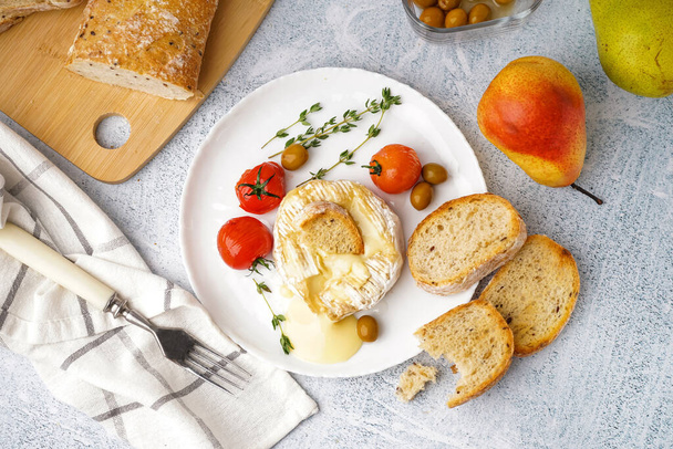 Placa de sabroso queso Camembert al horno sobre fondo claro - Foto, Imagen