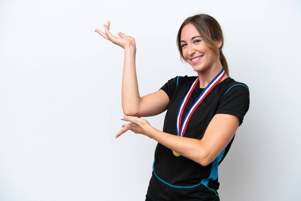 Young caucasian woman with medals isolated on white background extending hands to the side for inviting to come - Foto, Bild