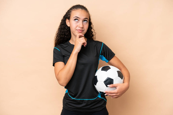 Mladý fotbalista žena izolované na béžové pozadí a vzhlíží - Fotografie, Obrázek