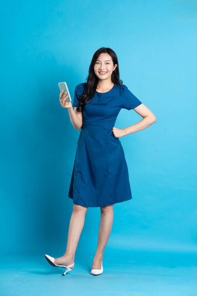 Portret van een mooie vrouw in blauwe jurk, geïsoleerd op blauwe achtergrond - Foto, afbeelding