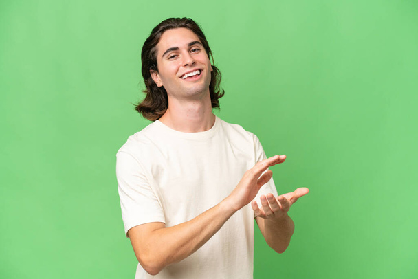 Young caucasian man isolated on green chroma background applauding - Photo, Image