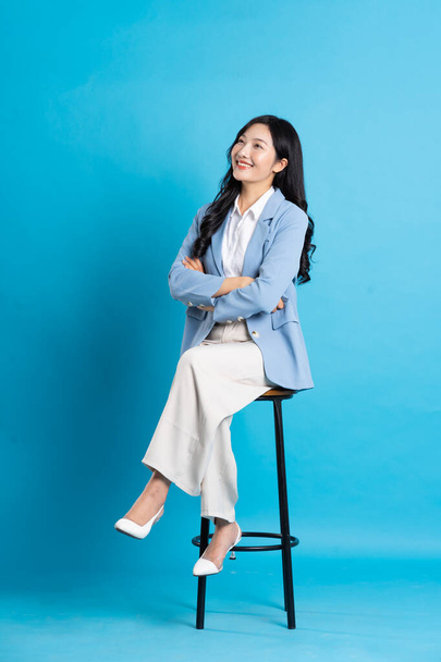 Ázsiai üzletasszony portré ül széken, elszigetelt kék háttér - Fotó, kép