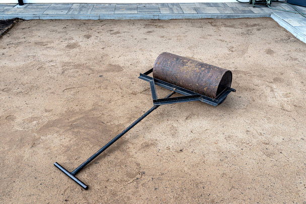 Rolling yellow sand with a steel roller for a garden pool. - Fotografie, Obrázek