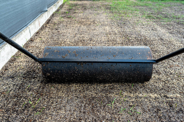 Rolling freshly sown grass seeds with a metal roller filled with water. - Fotoğraf, Görsel