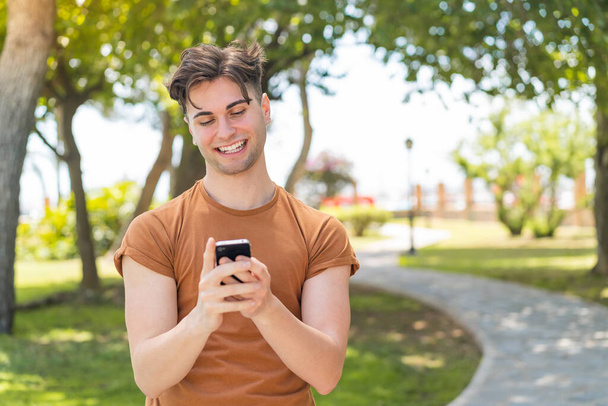 Joven hombre guapo enviando un mensaje con el móvil - Foto, Imagen