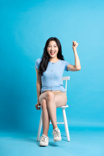 Ritratto di donna asiatica sorridente in posa su sfondo blu - Foto, immagini