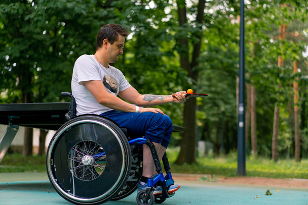 Inclusivité Un homme handicapé communique avec un homme âgé aux cheveux longs et à la barbe grise dans un parc urbain avec des arbres en arrière-plan - Photo, image