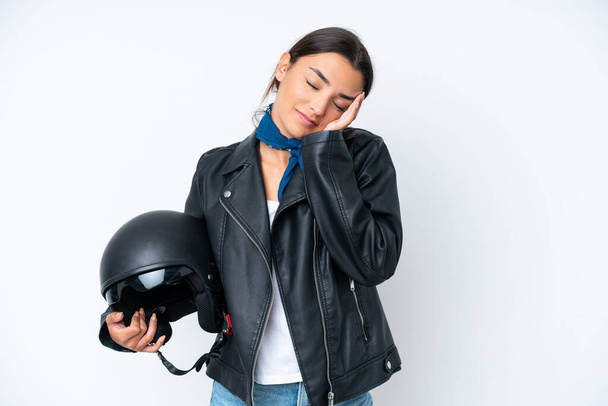 Νεαρή καυκάσια γυναίκα με κράνος μοτοσικλέτας απομονωμένη σε μπλε φόντο με πονοκέφαλο - Φωτογραφία, εικόνα