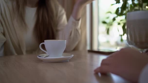 Twee vrouwen die zakenprojecten bespreken of het laatste nieuws in een café terwijl ze koffie drinken, close-up. Kopieerruimte - Video