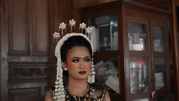 Jawajska panna młoda nosi jaśmin na głowie i makijaż na twarzy podczas ceremonii ślubnej - Materiał filmowy, wideo