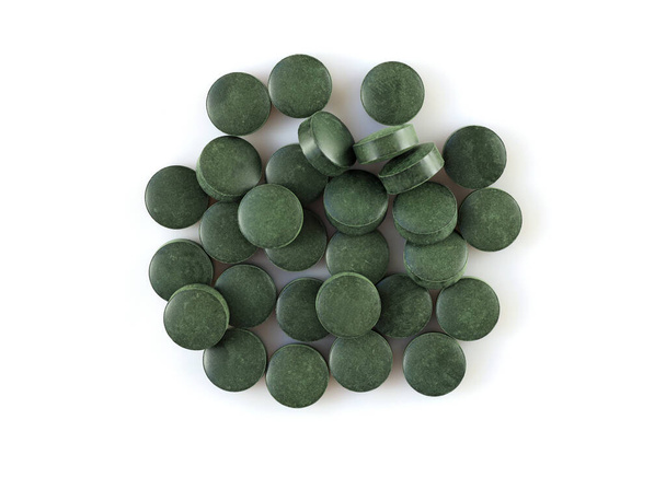 Tabletki Chlorella to suplementy diety. Spirulina w formie tabletek. Okrągłe zielone pigułki na białym tle widok z góry. sterta Spirulina tabletki suplement diety glony Flat lay - Zdjęcie, obraz