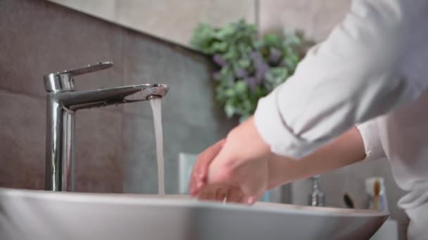 Hijyen, tatlı erkek çocuk ellerini yıkamak için sabun kullanıyor, lavaboda su ile sabun köpüklerini yıkıyor, elleri yakın plan. - Video, Çekim