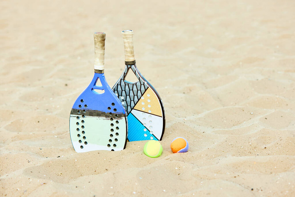 Paddle tennis racket and balls lying on sand. Summer type of game, warm outdoor training. Sport equipment. Concept of sport, leisure time, active lifestyle, hobby, game, summertime, ad - Φωτογραφία, εικόνα