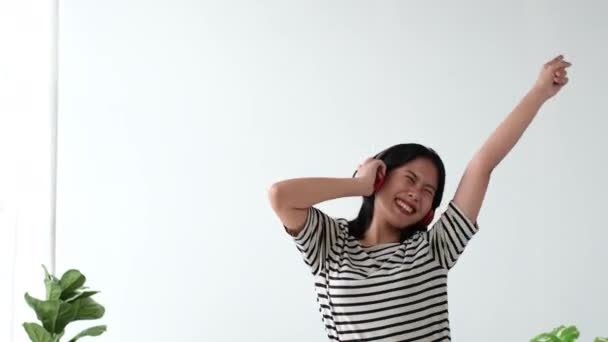 Boldog fiatal gyönyörű ázsiai fiatal nő hallgat zenét és táncol otthon. - Felvétel, videó