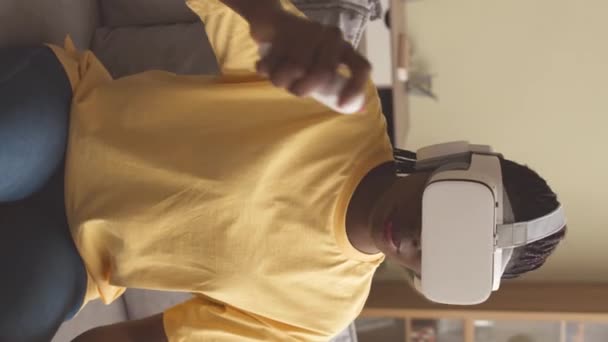 Κάθετη της Αφρικής American κορίτσι στα 20 της παίζοντας παιχνίδια VR στο σπίτι χρησιμοποιώντας το χειριστήριο τυχερών παιχνιδιών VR - Πλάνα, βίντεο