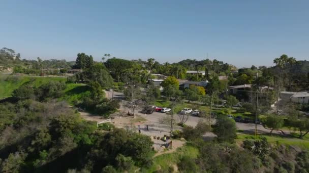 Voorwaarts vliegen boven residenties omgeven door veel groene tropische vegetatie. Residentiële stedelijke buurt aan de rand van de stad. Los Angeles, California, Verenigde Staten. - Video