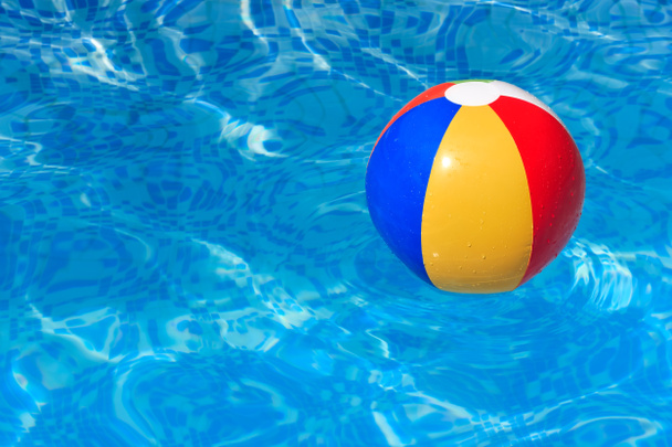 μια πολύχρωμη μπάλα παραλία που επιπλέει σε μια πισίνα - Φωτογραφία, εικόνα