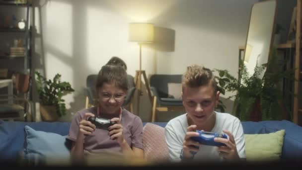 Ενθουσιασμένος έφηβος αγόρι και κορίτσι παίζουν μαζί βιντεοπαιχνίδι το βράδυ στο σπίτι - Πλάνα, βίντεο