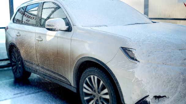 Primer plano de la aplicación de espuma en el coche sucio en el servicio de lavado. Cuidado del automóvil, limpieza del transporte, coche sucio - Foto, Imagen