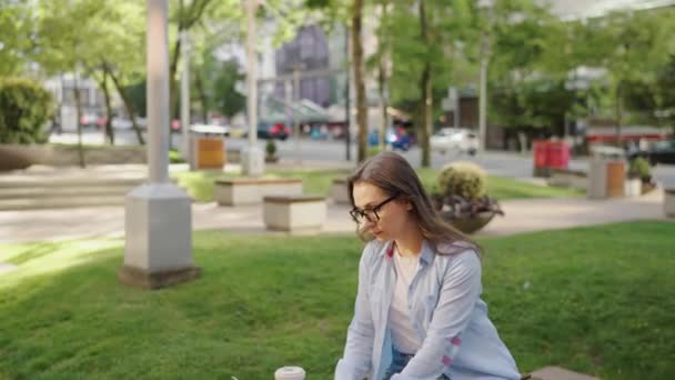 Femme d'affaires insouciante s'assoit à l'extérieur avec du café et en utilisant un ordinateur portable, travail à distance. - Séquence, vidéo