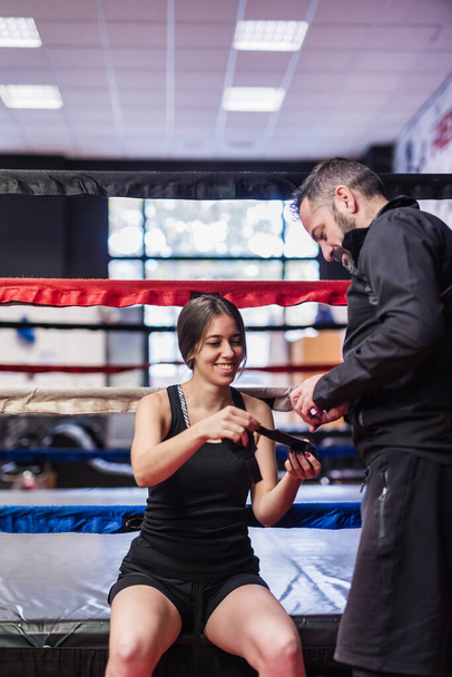 Artes marciales y gerente de autodefensa ayudan a un boxeador o boxeador a poner las envolturas protectoras del equipo de ropa deportiva. - Foto, Imagen