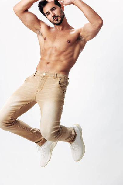 Modelo de moda masculina com um tronco nu e abs packs pulando em um fundo isolado branco, estilo de roupa elegante, espaço de cópia, espaço para texto. Foto de alta qualidade - Foto, Imagem
