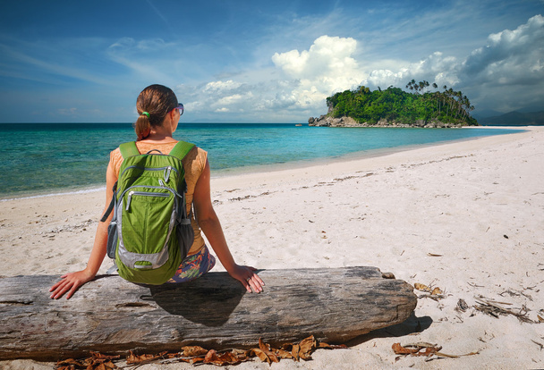 junge Frau mit Rucksack entspannt sich an der Küste und blickt auf eine Insel - Foto, Bild