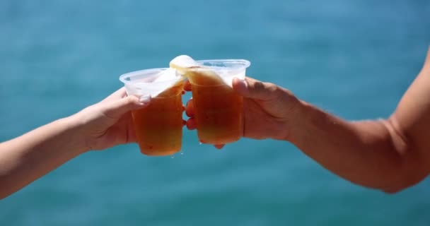 Plajda, insanların elleri plastik bardakta bira ile birbirine vuruyor, yakın plan. Deniz tatilinde alkol kavramı - Video, Çekim