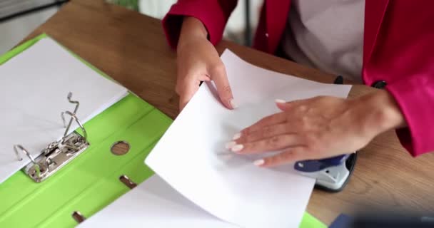 Masadaki bir kadın delikli yumruk kullanıyor, yakın plan, yavaş çekim. Ofis evrensel aracı, kağıt delme - Video, Çekim