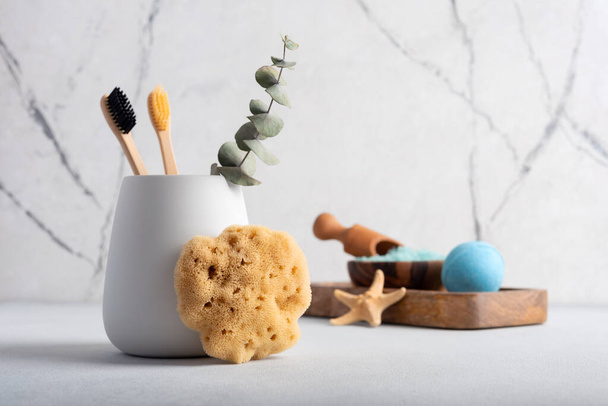 Eco-friendly bathroom accessories: bamboo toothbrush and natural sea sponge. Zero waste spa and bath products.  - Foto, Imagen