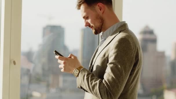 Close-up de um homem mãos segurando um smartphone moderno. Empresário andando enquanto digita em seu telefone celular. Um relógio de pulso de luxo numa mão de homem em primeiro plano. Um fato preto clássico. Negócios - Filmagem, Vídeo