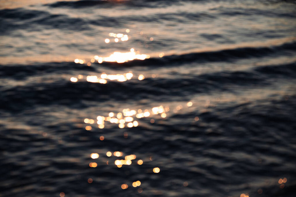 Blurred frame with small waves in which the rays of the sun are reflected. High quality photo - Photo, Image
