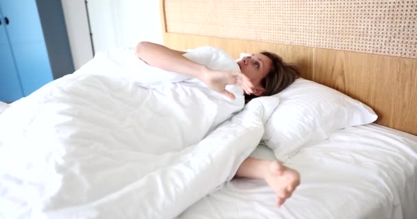 La donna si sveglia sul letto da sola, primo piano. Comodo letto, camera da letto in hotel, biancheria da letto bianca - Filmati, video