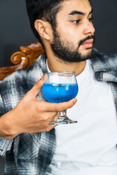 専門的に構成されて,イメージはあなたのマーケティング材料を高めるために理想的な彼の手で青い色の飲み物を寄付する男を描きます - 写真・画像