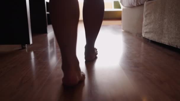 裸足の女性の足が光の中でウィンドウに向かって歩く-ボディポジティブ - 映像、動画