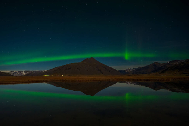 Aurora Boreal o auroras boreales la maravilla asombrosa de la naturaleza en los cielos dramáticos de Islandia. Paisaje nocturno con la luz verde en una hermosa danza reflejada como un espejo - Foto, imagen