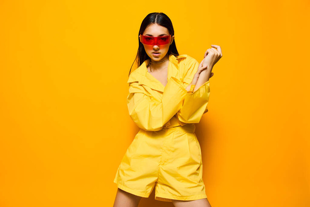 стильная женщина желтый наряд гламурные солнцезащитные очки брюнетки образ жизни молодые длинные волосы веселые привлекательные модные моды красивые монохромный стиль кавказская девушка радость - Фото, изображение