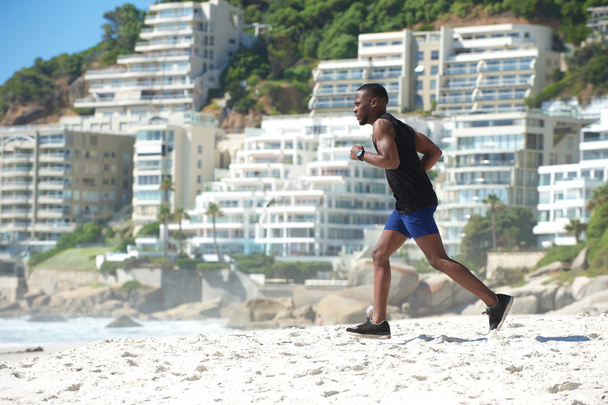Alkalmas fiatal férfi fut a strandon - Fotó, kép