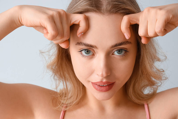 Young woman doing face building exercise on light background, closeup - Photo, Image