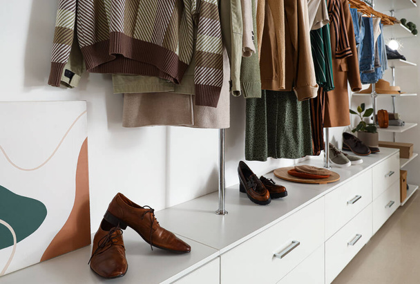 Roupas elegantes com sapatos modernos em boutique, close-up - Foto, Imagem