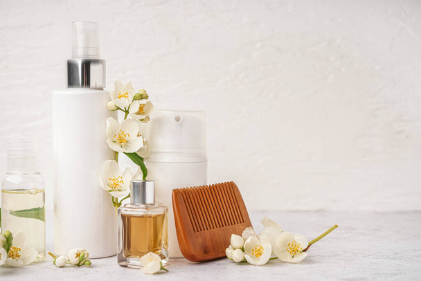 Set van cosmetische producten, haarkam en mooie jasmijnbloemen op lichte ondergrond - Foto, afbeelding