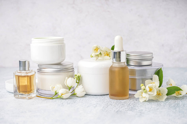 Sada různých kosmetických výrobků a krásné jasmínové květy na světlém pozadí - Fotografie, Obrázek